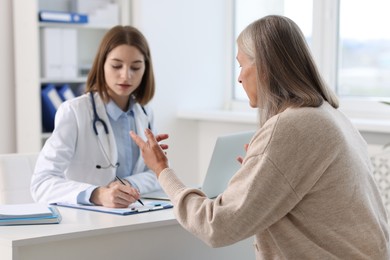 Photo of Young healthcare worker consulting senior patient in hospital