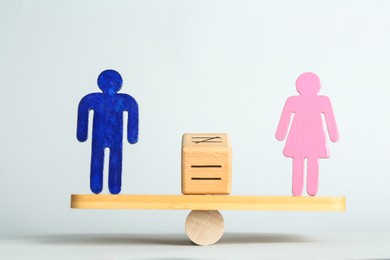 Photo of Gender equality concept. Male and female figures on scales against light background