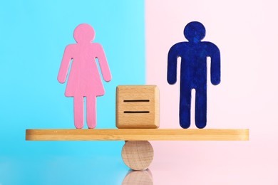 Photo of Gender equality concept. Cube with equals sign between male and female figures on scales against color background