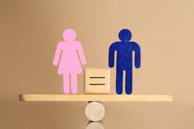 Photo of Gender equality concept. Cube with equals sign between male and female figures on scales against beige background