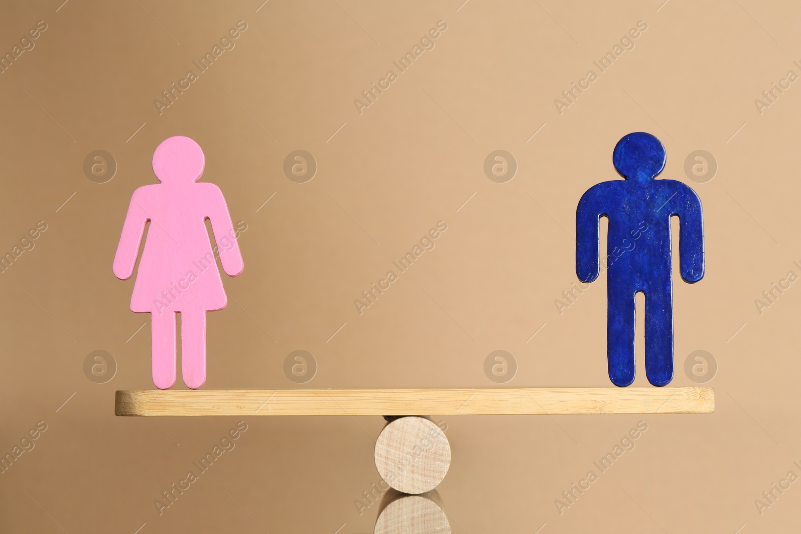 Photo of Gender equality concept. Male and female figures on scales against beige background