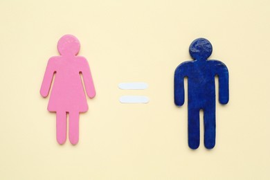 Photo of Gender equality concept. Male and female figures on beige background, flat lay