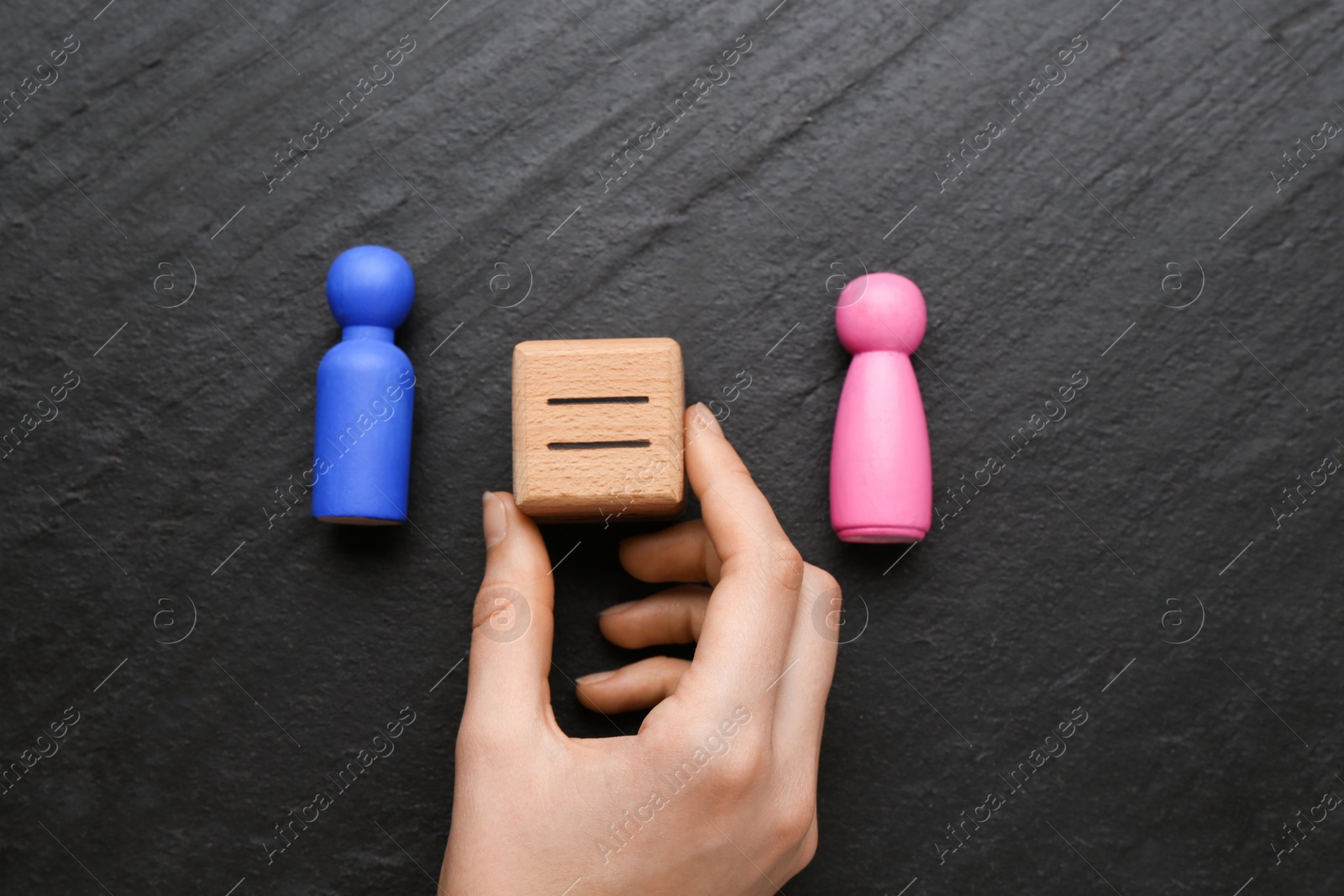 Photo of Gender equality concept. Woman holding wooden cube with equals sign between female and male figures at grey textured background, top view