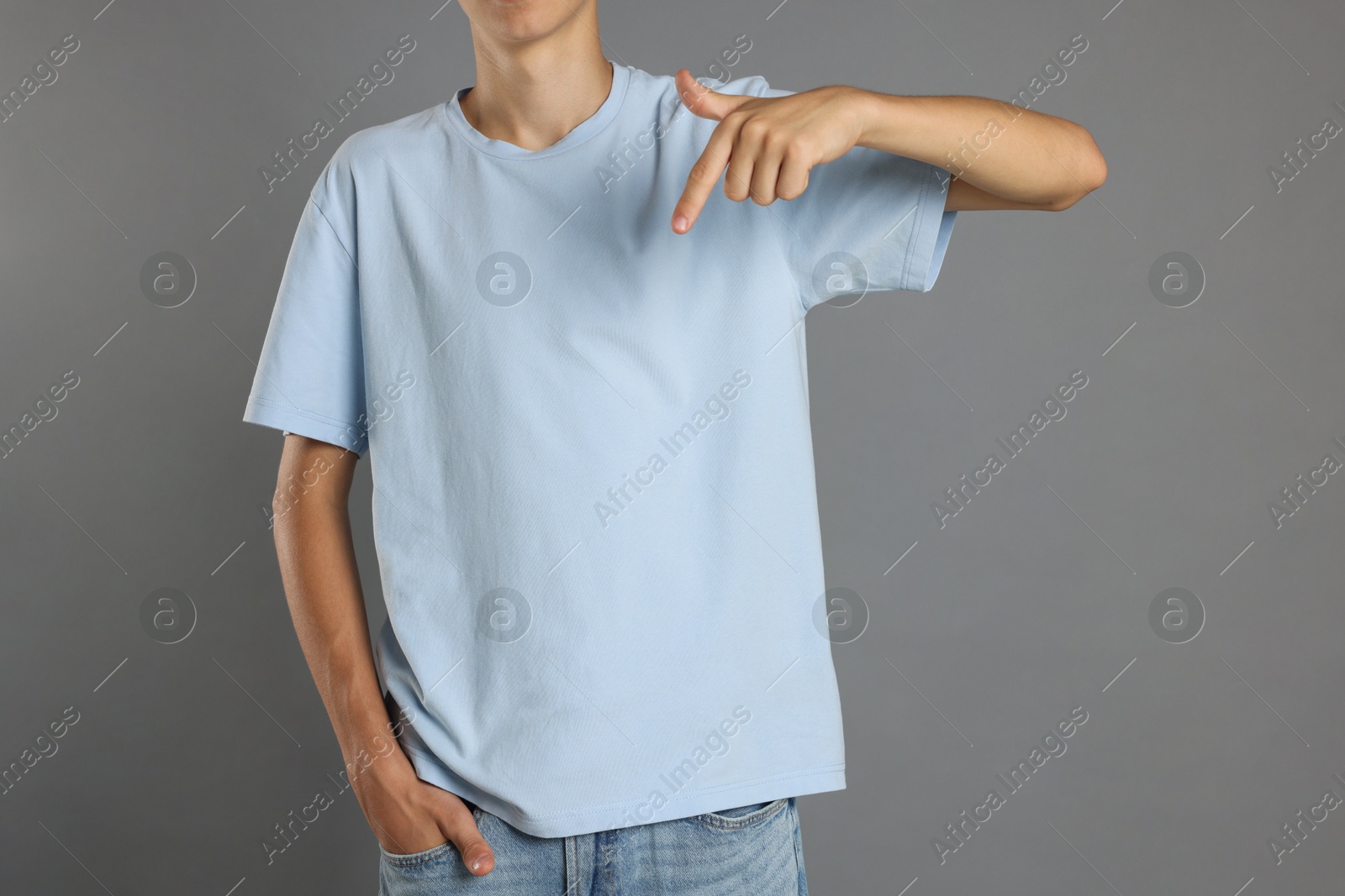 Photo of Teenage boy wearing light blue t-shirt on grey background, closeup