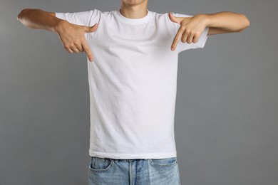 Teenage boy wearing white t-shirt on grey background, closeup