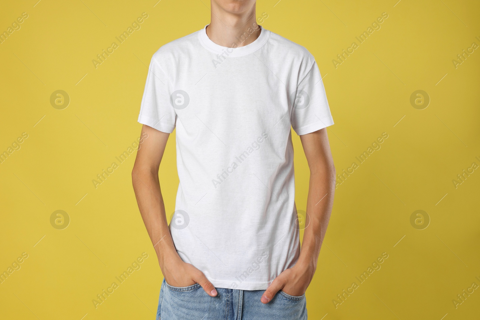 Photo of Teenage boy wearing white t-shirt on yellow background, closeup