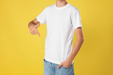 Photo of Teenage boy wearing white t-shirt on yellow background, closeup