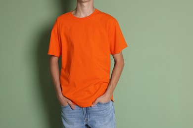 Photo of Teenage boy wearing orange t-shirt on green background, closeup