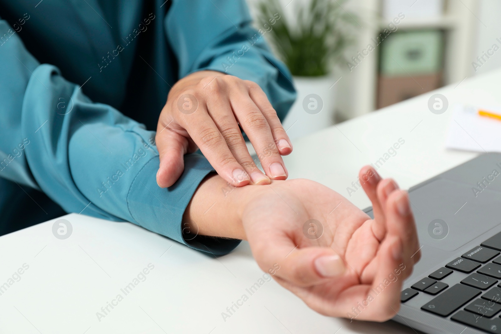 Photo of Carpal tunnel syndrome. Woman suffering from pain in wrist at desk indoors, closeup