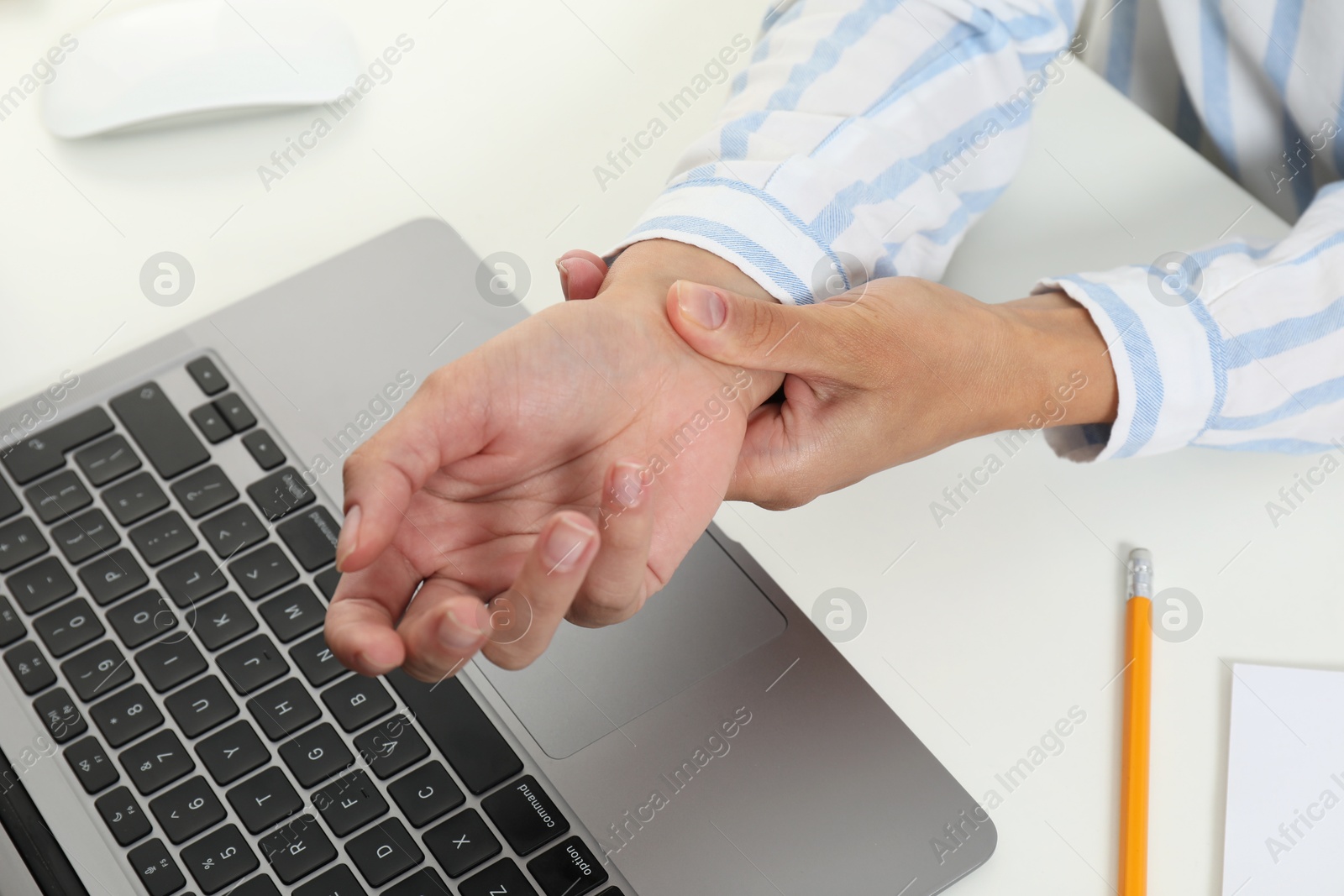 Photo of Carpal tunnel syndrome. Woman suffering from pain in wrist at desk, closeup