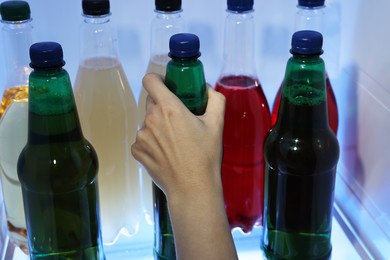 Photo of Woman taking bottle with drink from refrigerator, closeup