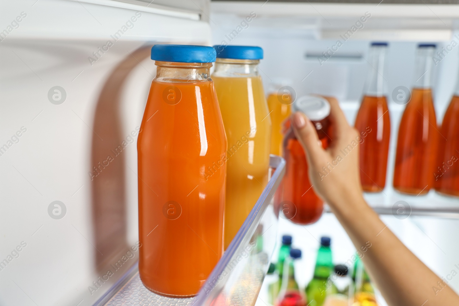 Photo of Woman taking bottle with drink from refrigerator, closeup