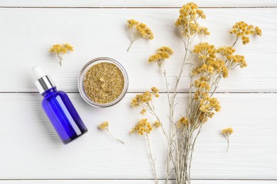 Photo of Bottle of tincture and helichrysum flowers on white wooden table, flat lay