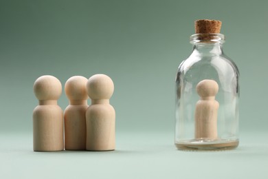 Photo of Loneliness concept. Human figure in bottle isolated from others on light green background