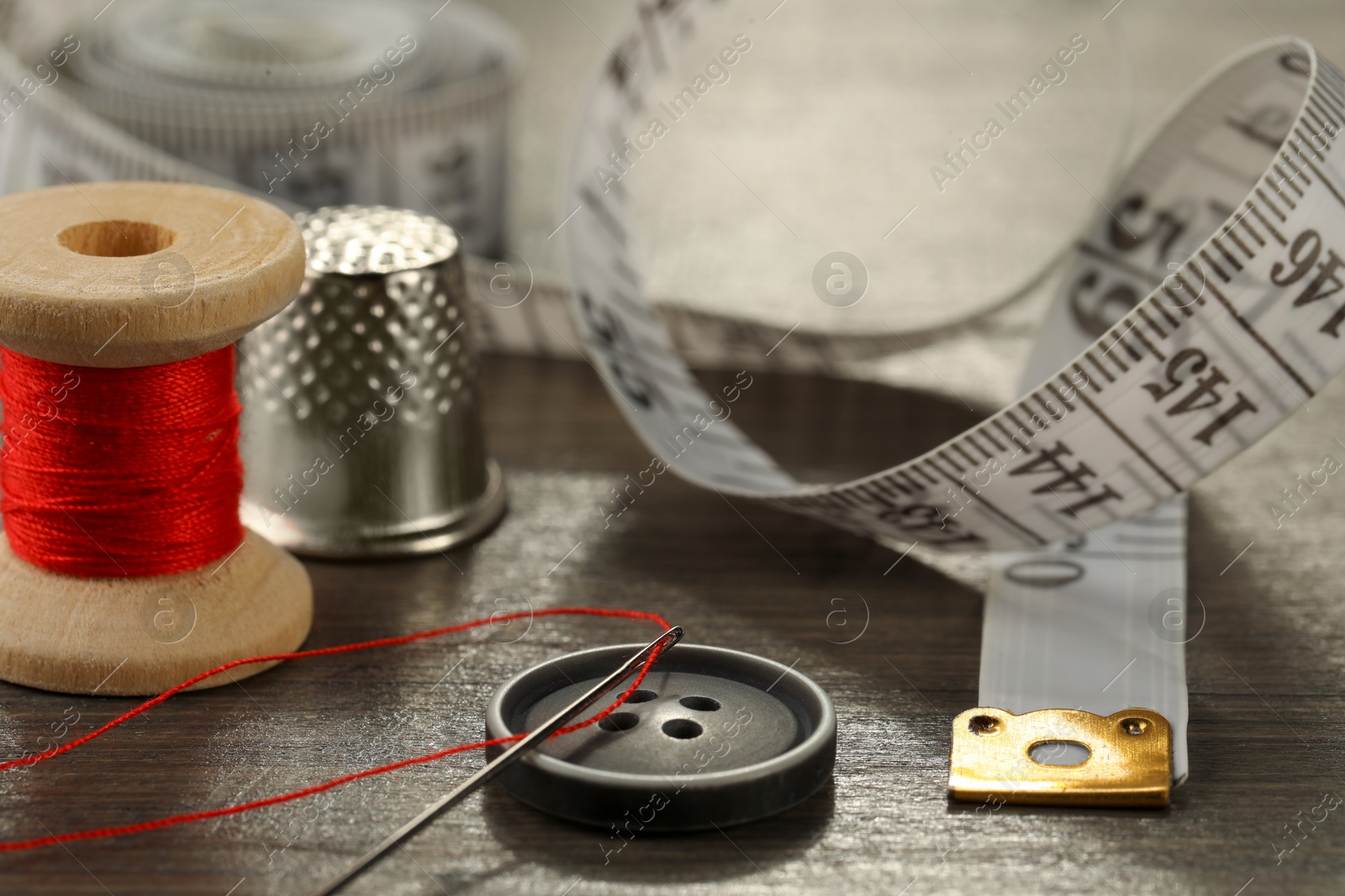 Photo of Different sewing tools on wooden table, closeup