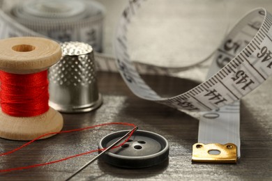 Photo of Different sewing tools on wooden table, closeup