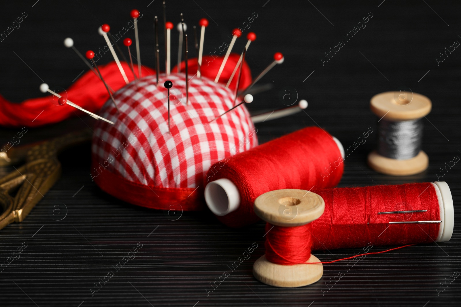 Photo of Different sewing tools on wooden table, closeup