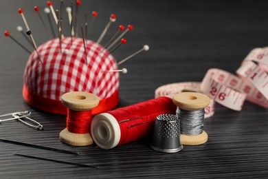 Photo of Different sewing tools on wooden table, closeup