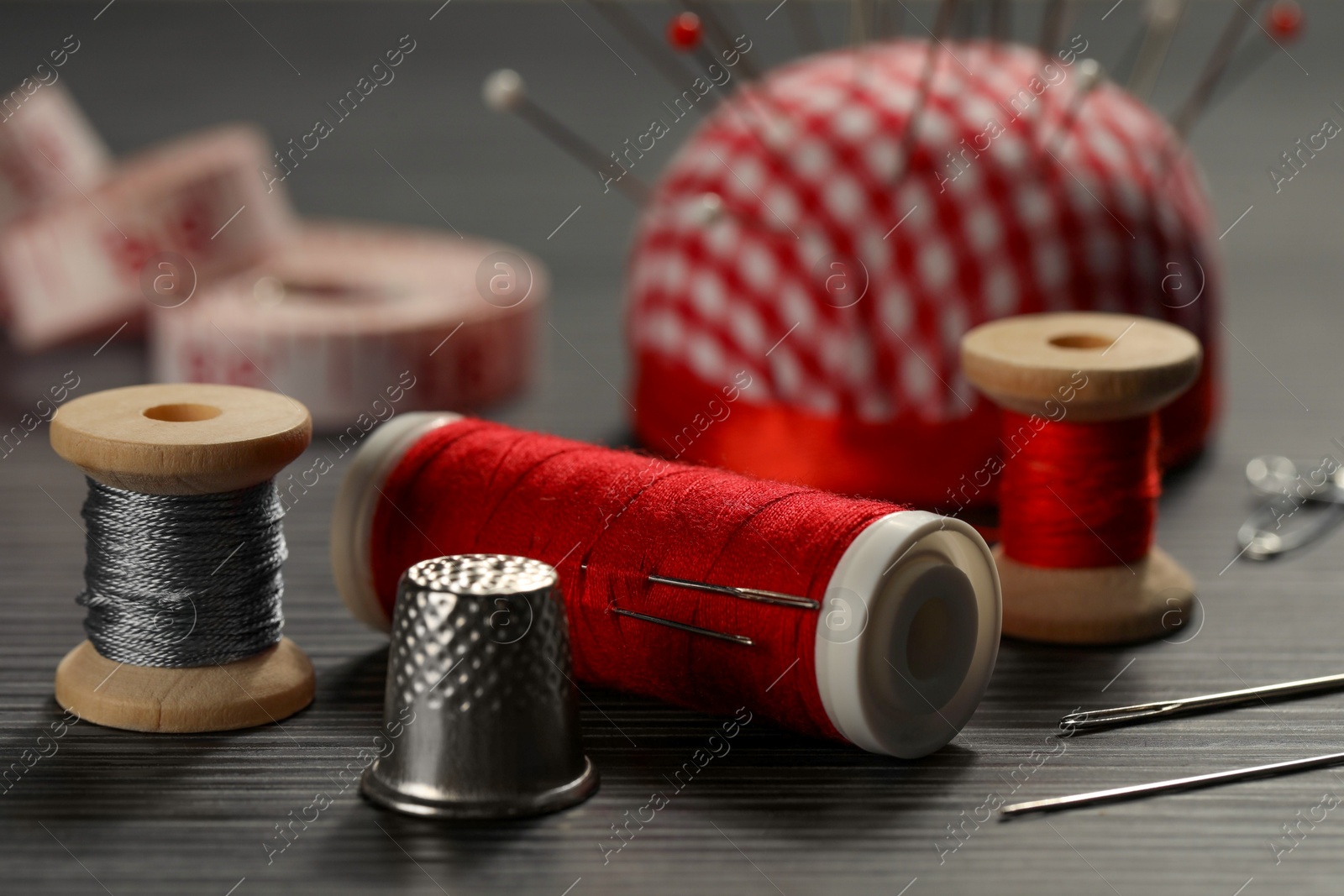 Photo of Different sewing tools on wooden table, closeup