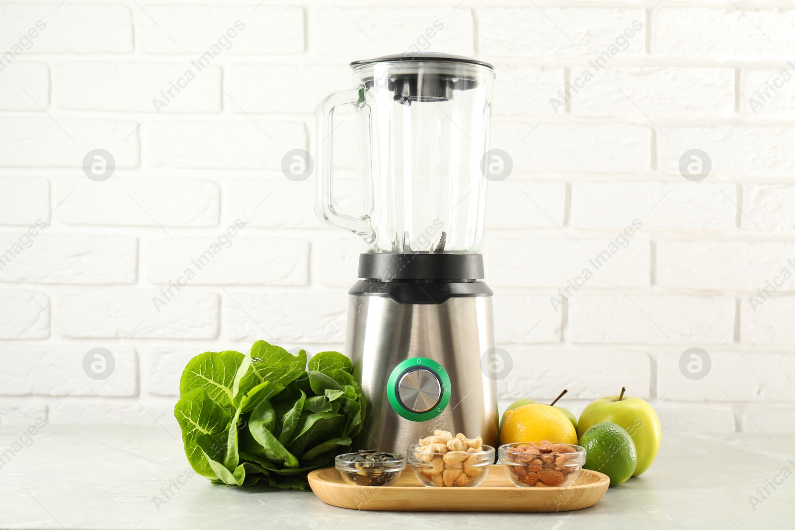 Photo of Blender and products on light table against white brick wall