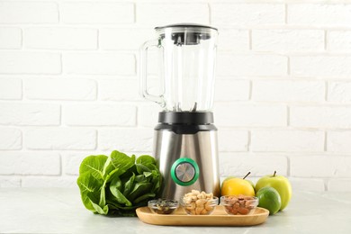 Photo of Blender and products on light table against white brick wall