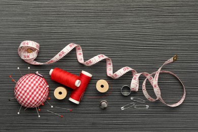 Photo of Different sewing tools on wooden table, flat lay