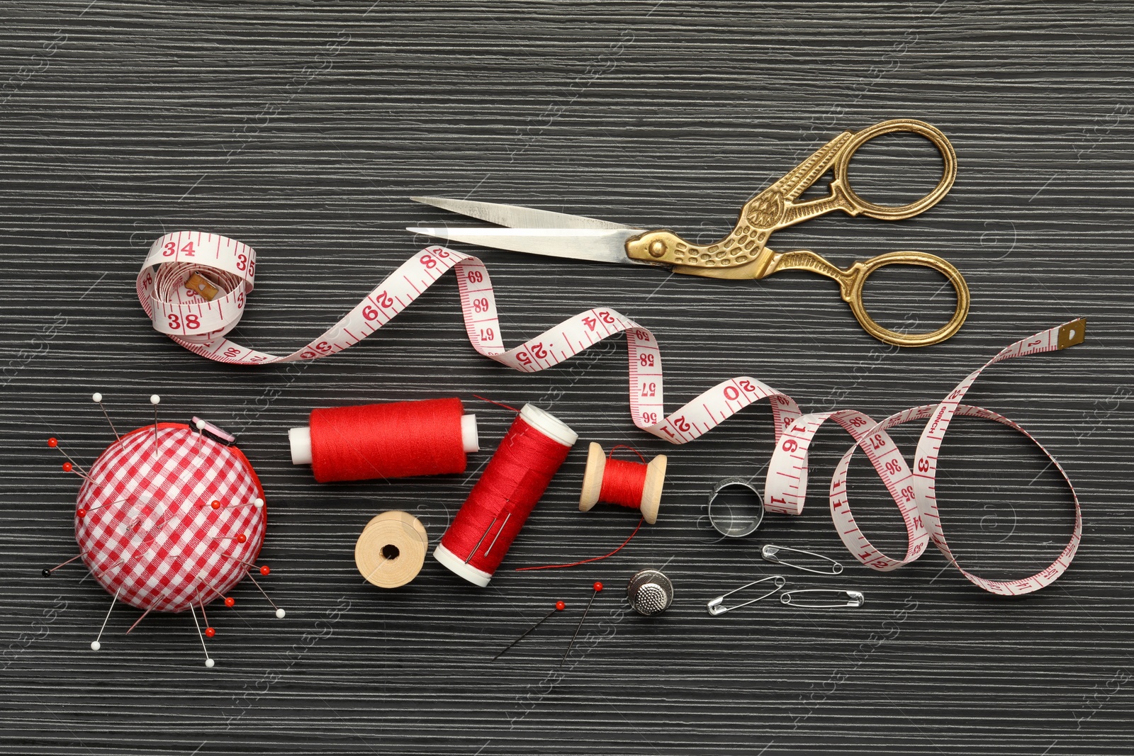 Photo of Different sewing tools on wooden table, flat lay