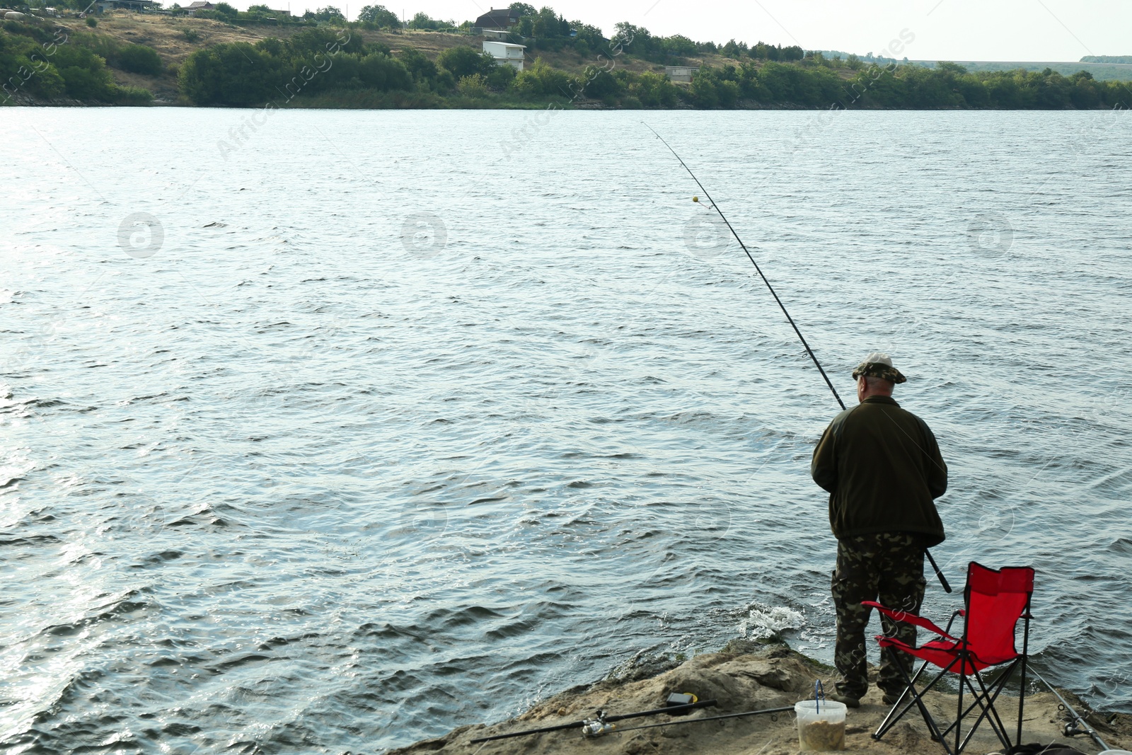 Photo of Fisherman with rod fishing near lake at summer, back view. Space for text