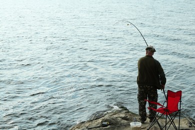 Fisherman with rod fishing near lake at summer, back view. Space for text