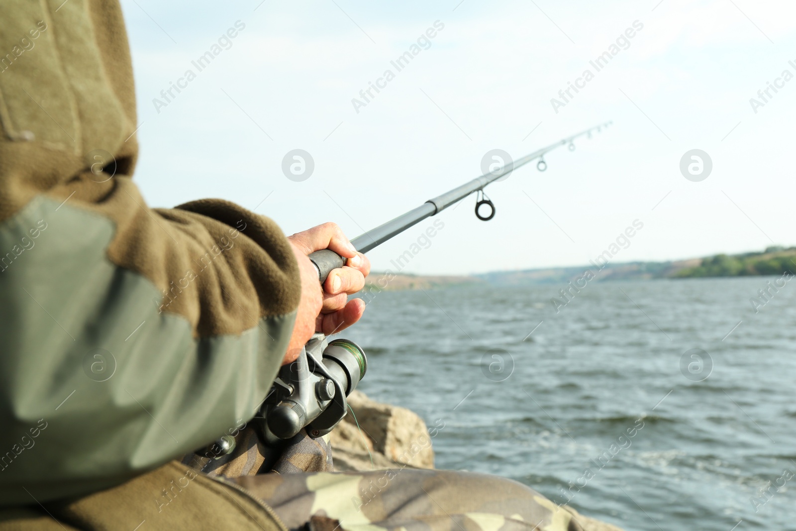 Photo of Fisherman with rod fishing near lake at summer, closeup