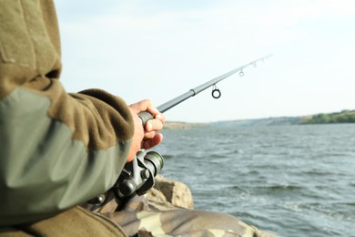 Fisherman with rod fishing near lake at summer, closeup