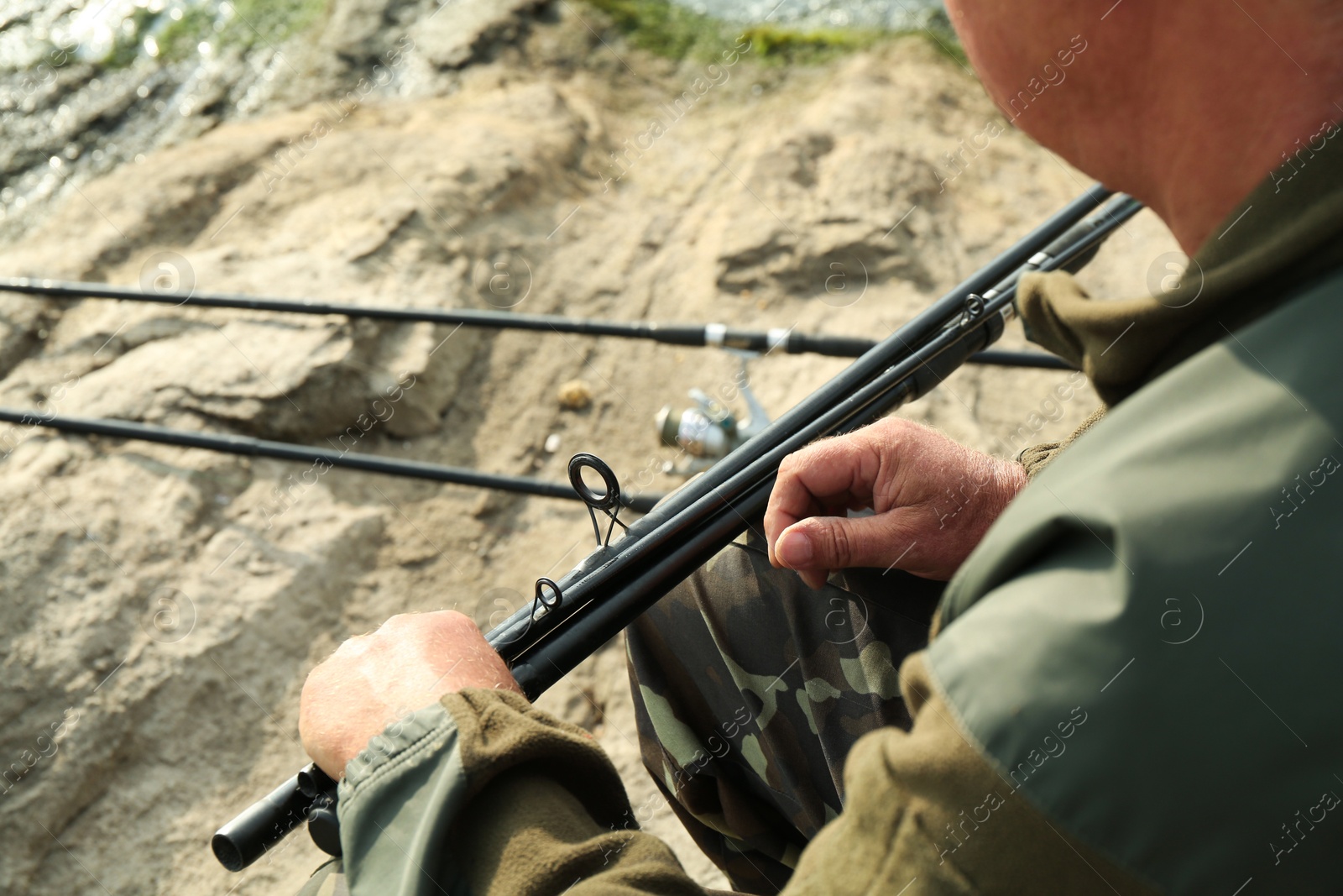 Photo of Fisherman with rod fishing near lake at summer, closeup