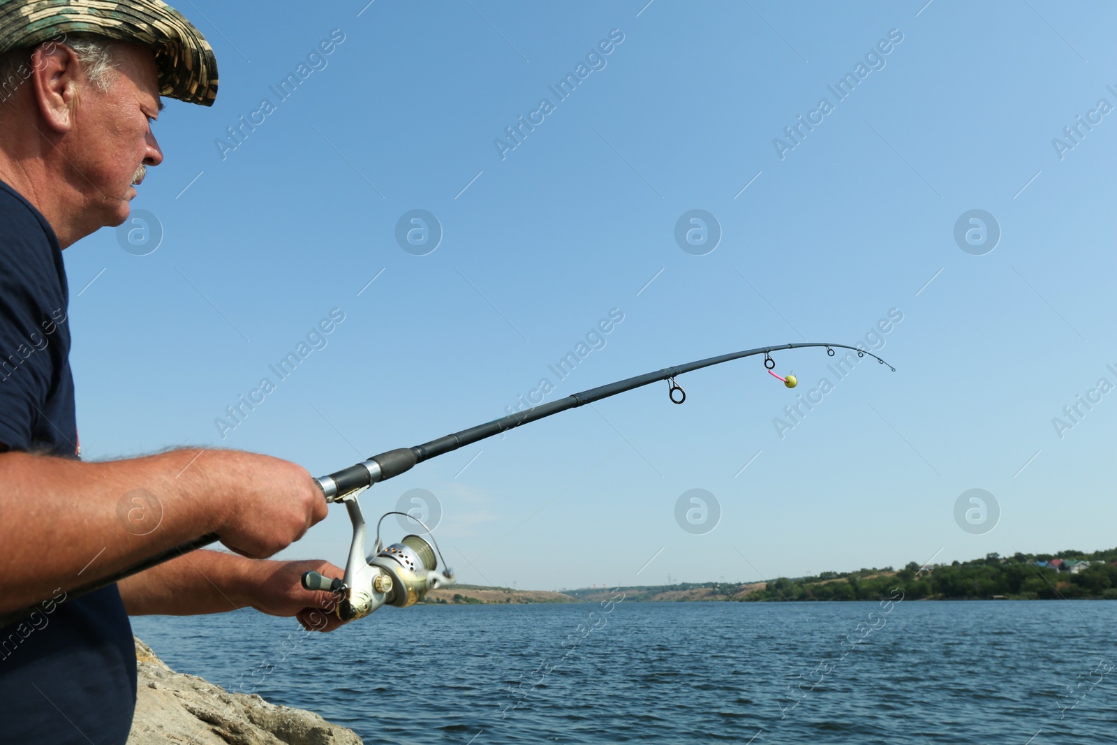 Photo of Fisherman with rod fishing near lake at summer