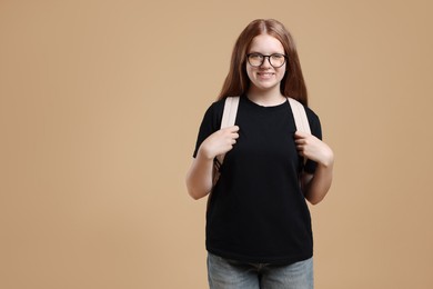 Teenage girl with backpack on beige background, space for text