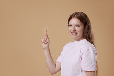 Portrait of teenage girl on beige background, space for text