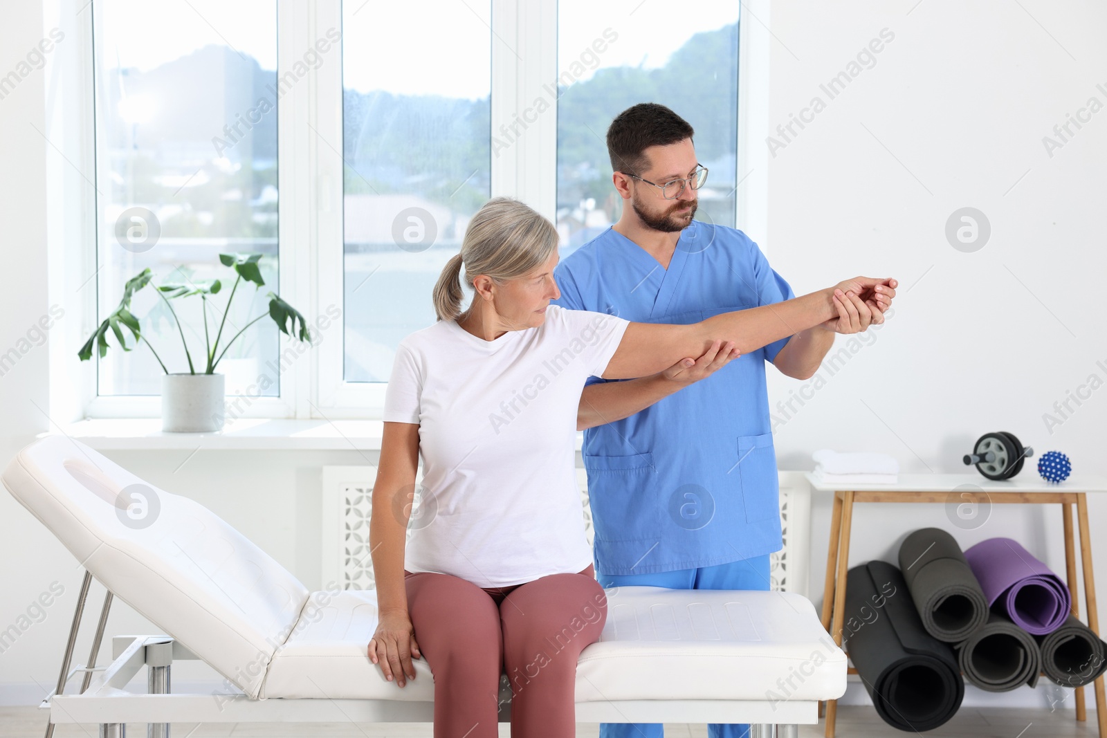 Photo of Physiotherapist working with senior patient in rehabilitation center