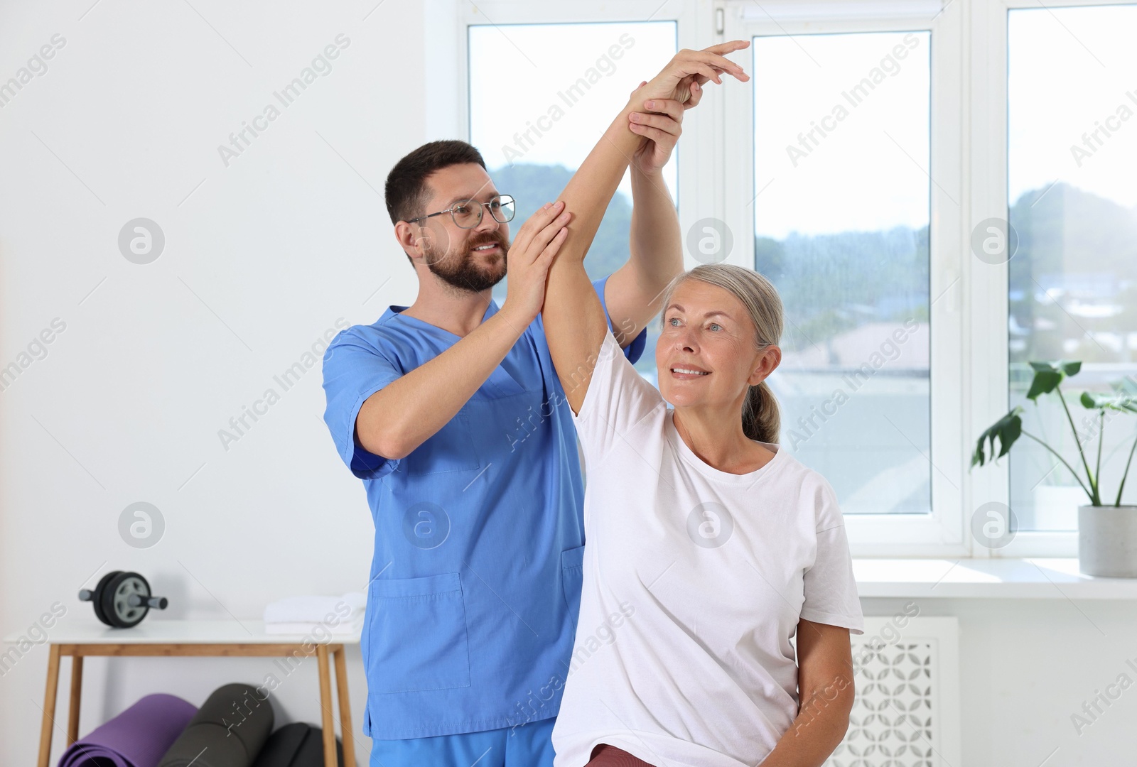 Photo of Physiotherapist working with senior patient in rehabilitation center