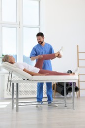 Photo of Physiotherapist working with senior patient in rehabilitation center