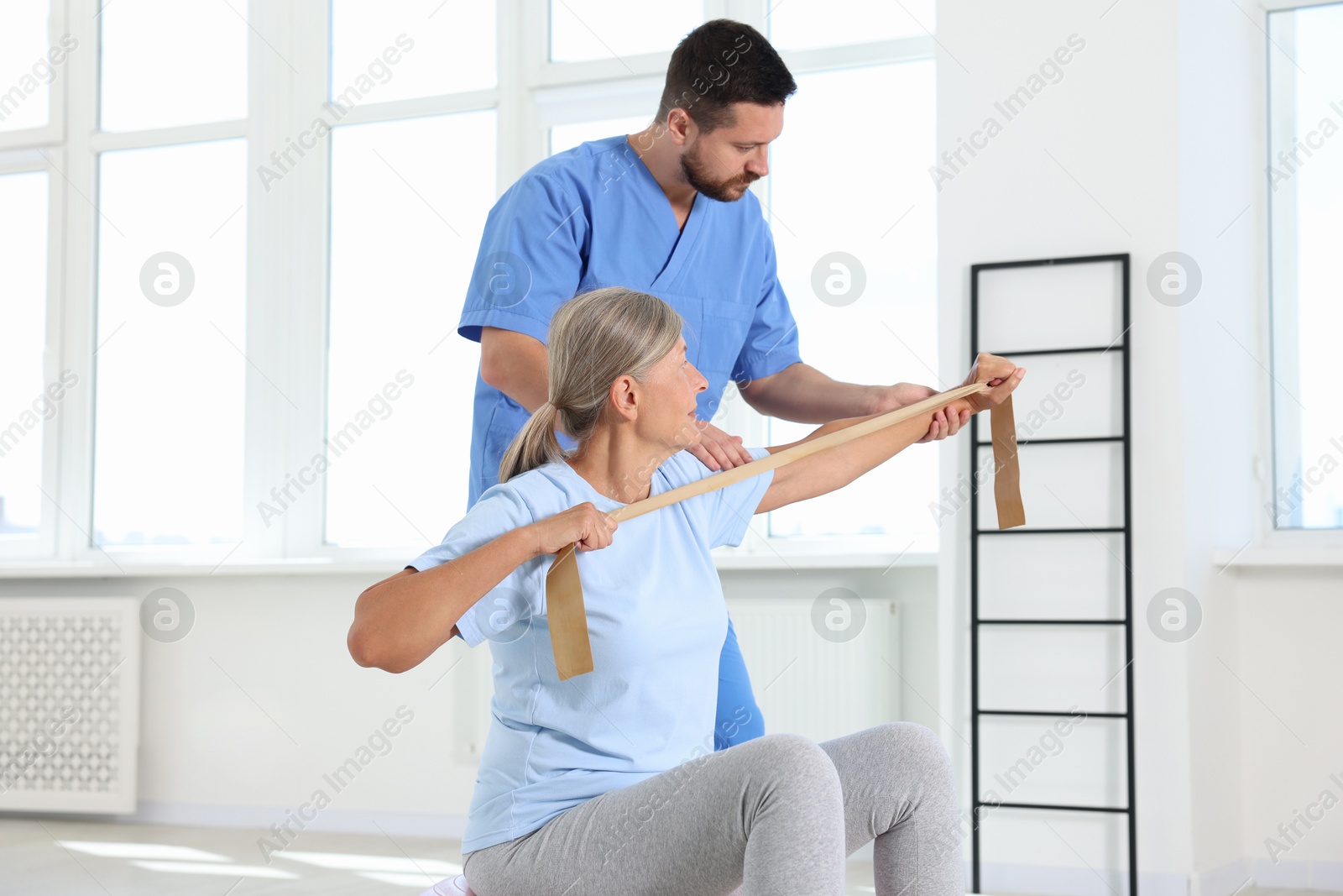 Photo of Senior patient exercising under physiotherapist supervision in rehabilitation center