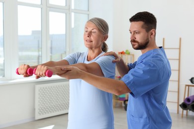 Photo of Senior patient exercising under physiotherapist supervision in rehabilitation center