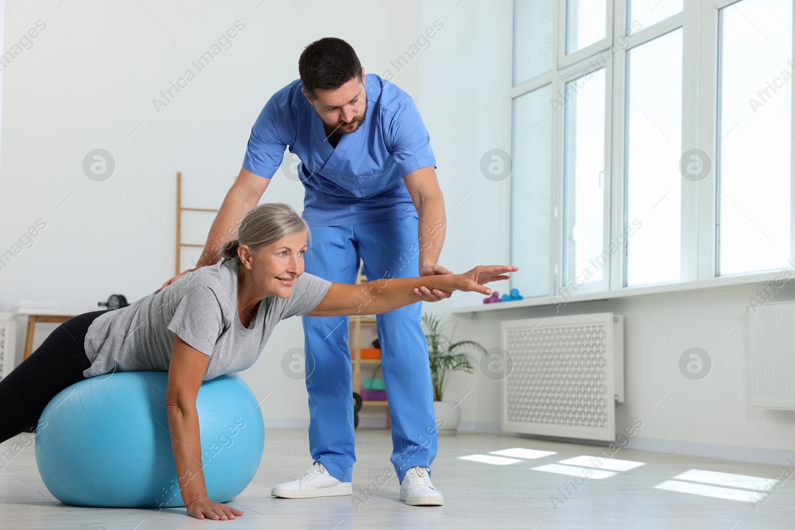 Photo of Physiotherapist working with senior patient in rehabilitation center