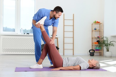 Photo of Physiotherapist working with senior patient in rehabilitation center