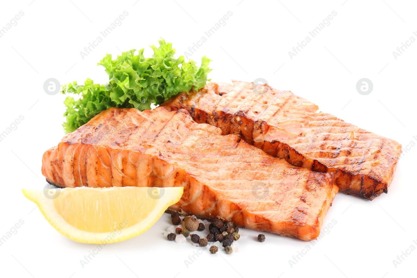 Photo of Delicious grilled salmon fillets with peppercorns, lemon and lettuce isolated on white