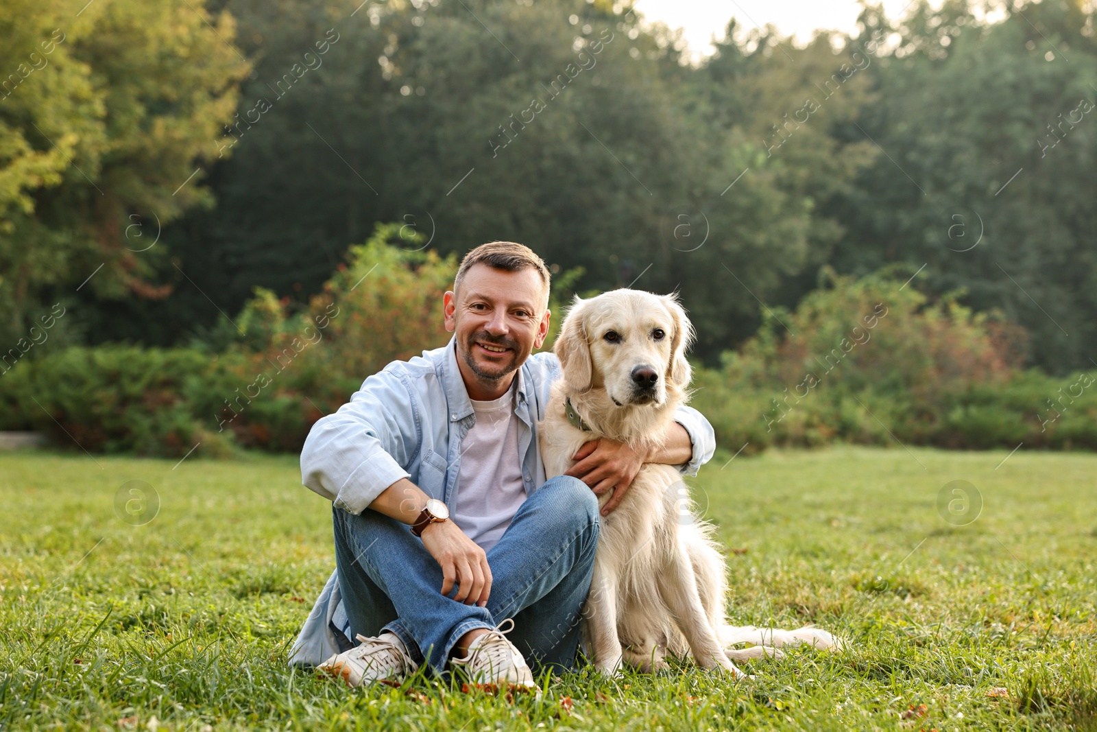 Photo of Smiling man with cute Golden Retriever dog on spring day