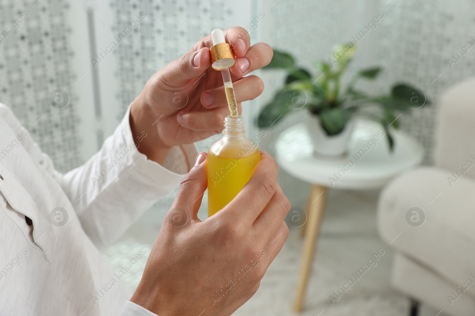 Photo of Young man taking CBD tincture indoors, closeup