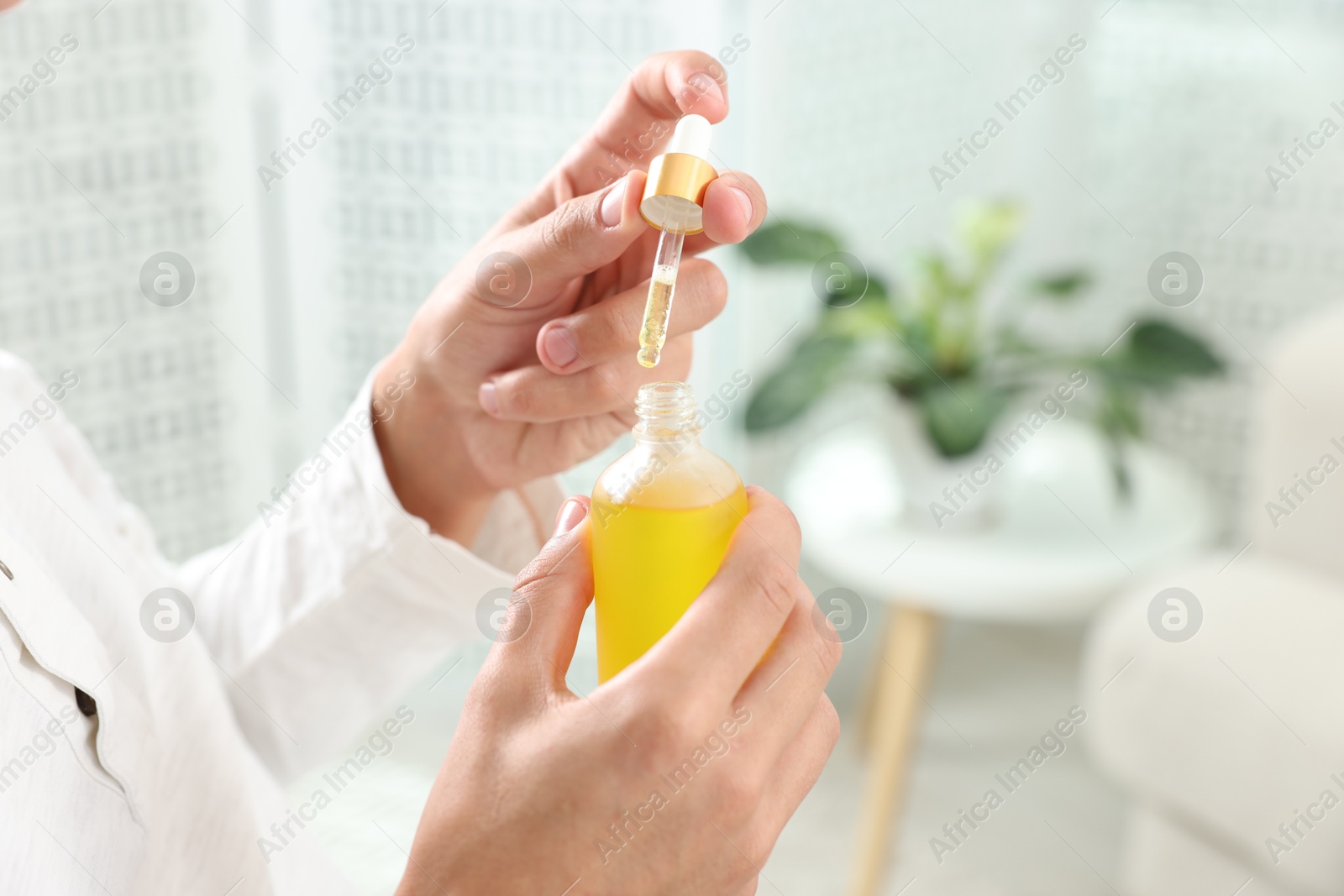 Photo of Young man taking CBD tincture indoors, closeup