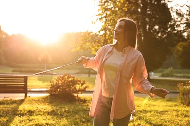 Photo of Happy young woman with playing badminton in park on sunny day