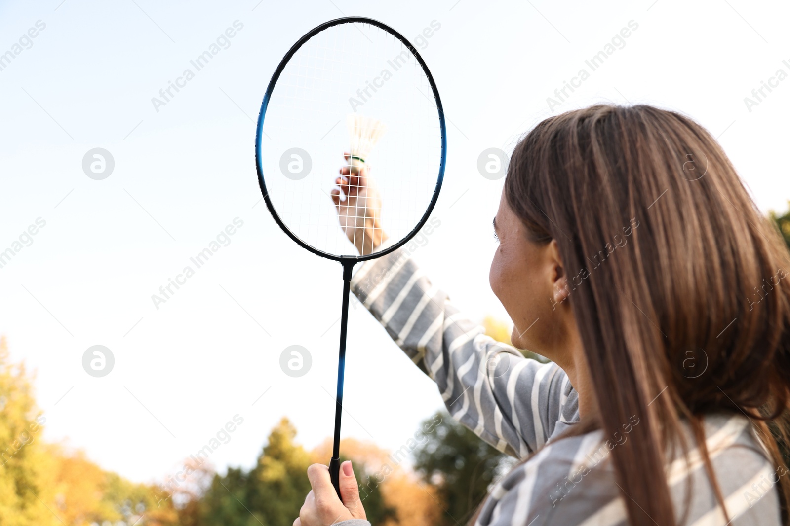 Photo of Young woman with badminton racket and shuttlecock in park, low angle view