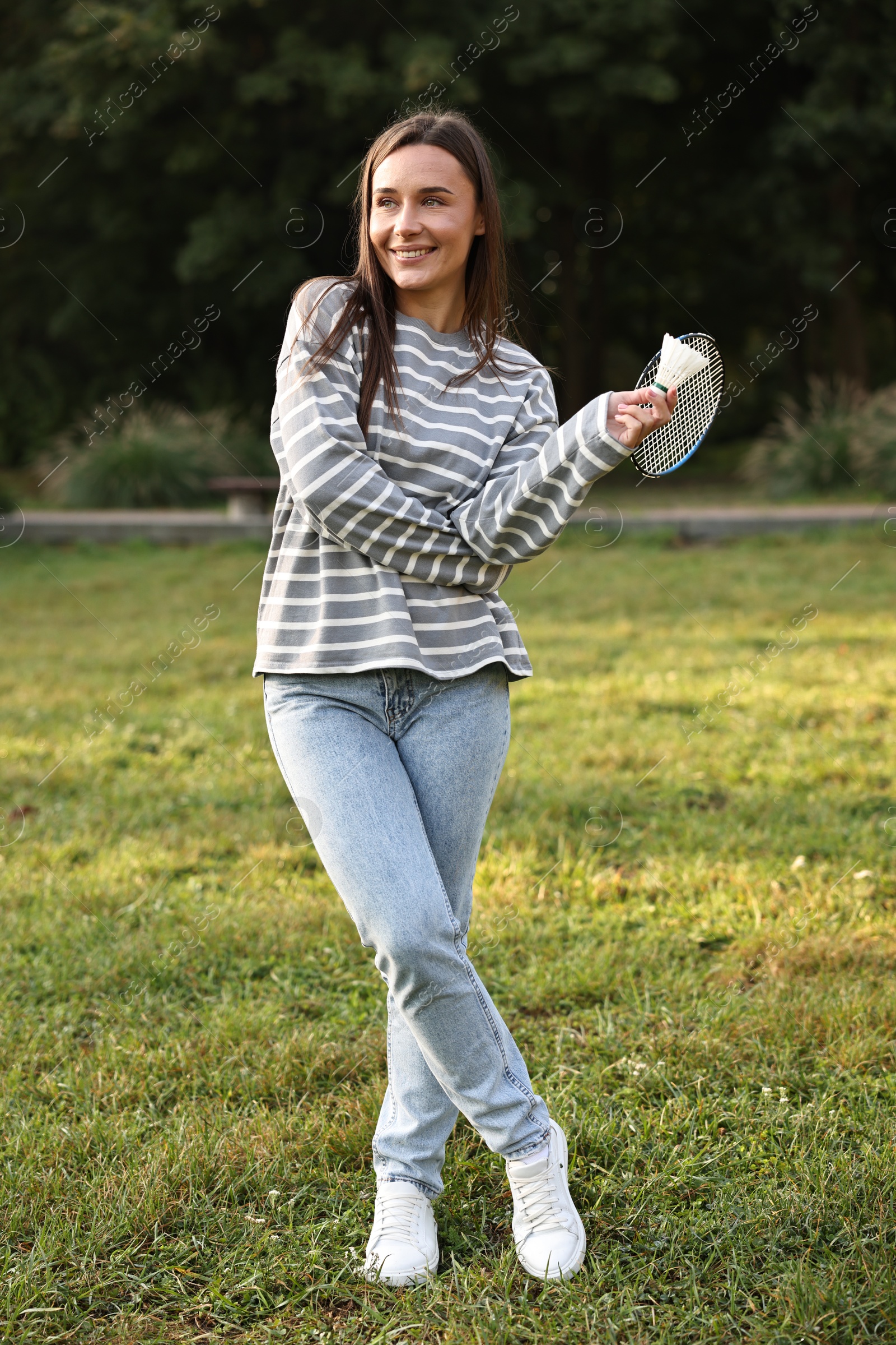 Photo of Happy young woman with badminton racket and shuttlecock in park