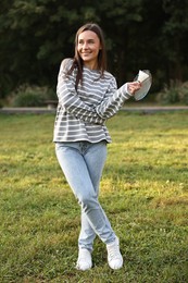 Photo of Happy young woman with badminton racket and shuttlecock in park